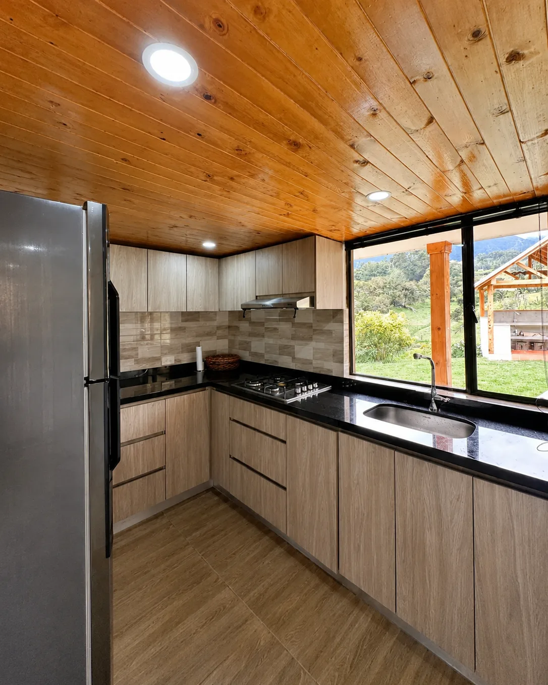 Cocina en L de Casa Neusa, con nevera y ventana sobre el fregadero