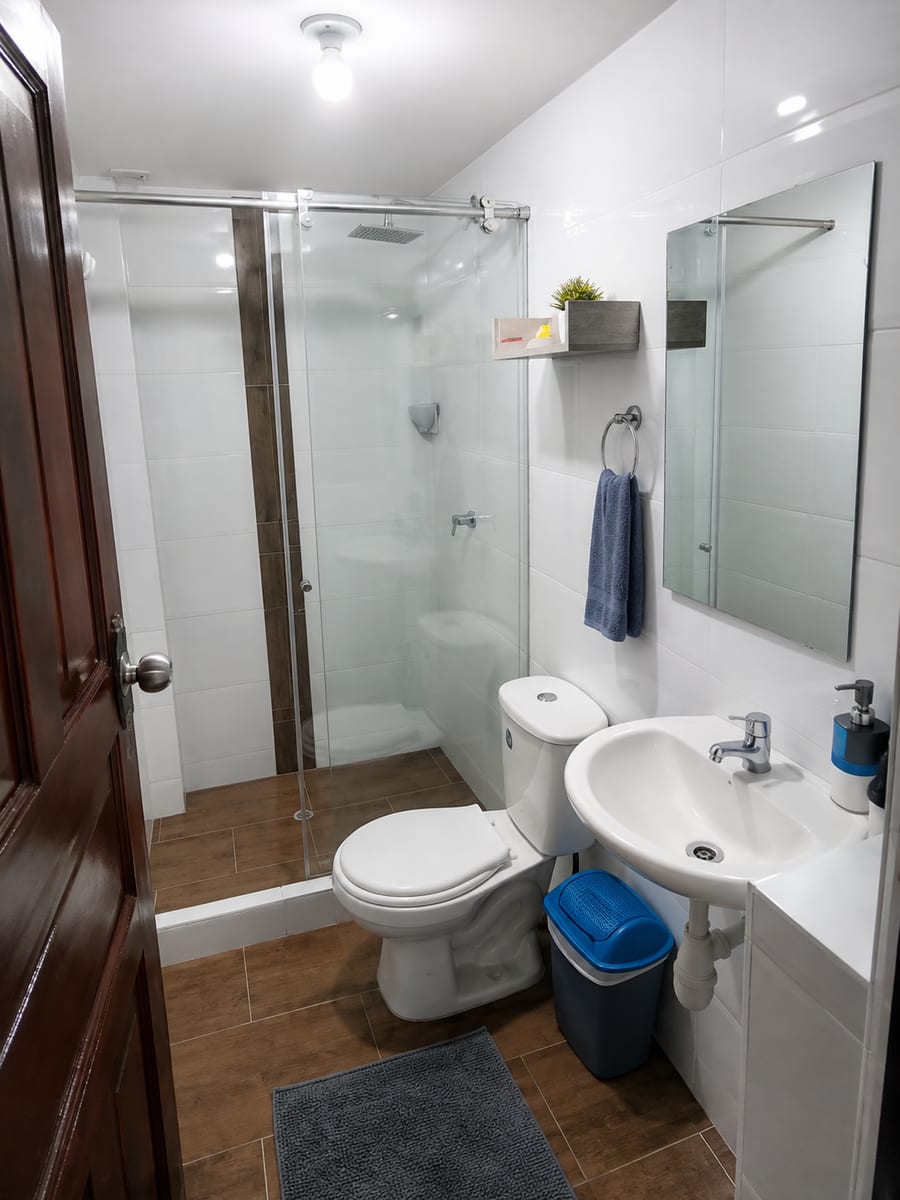 Bano compartido del segundo piso, con ducha de vidrio, sanitario y lavamanos