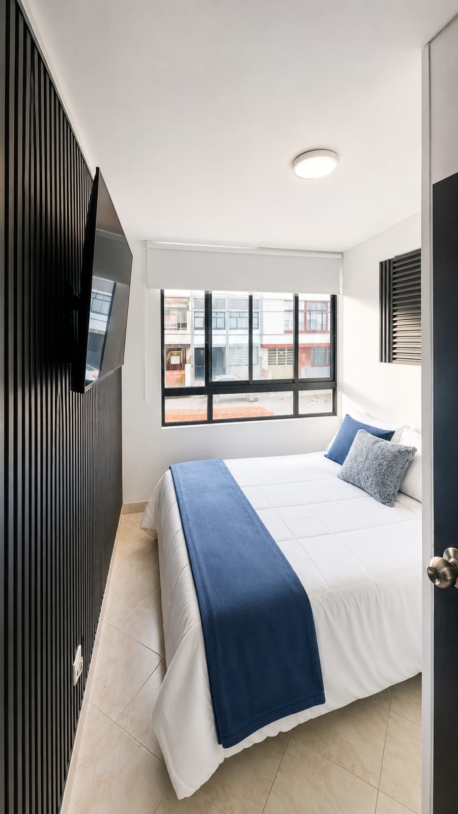 Habitación 201 con cama doble, televisión en la pared de listones y ventana a la calle