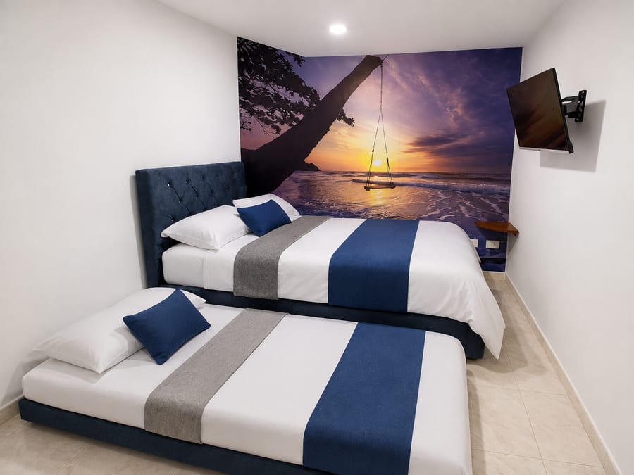 Cama nido de la habitación 203 desplegada junto a la cama principal, con la televisión al fondo
