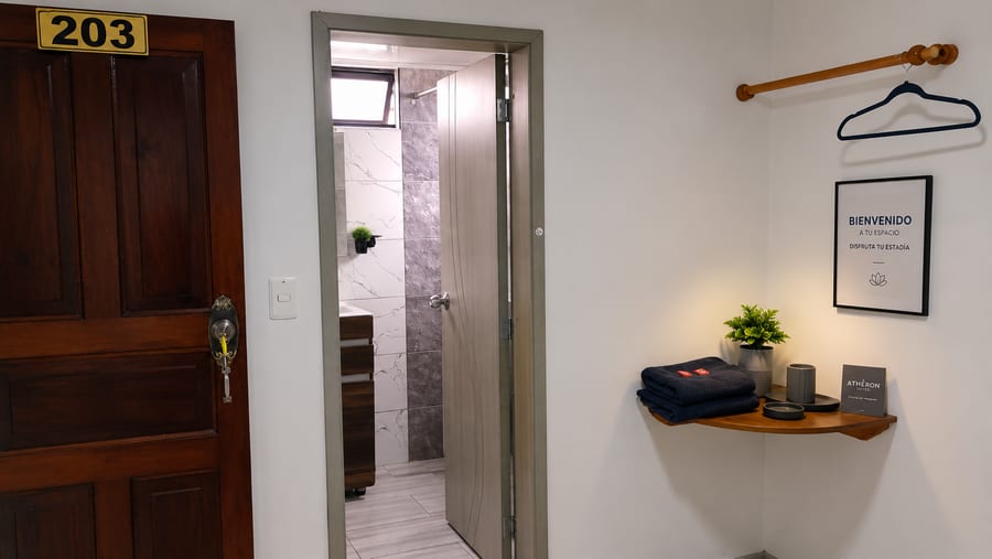 Entrada del bano privado de la habitación 203, con toallas y percha junto a la puerta