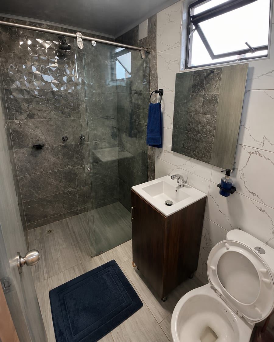 Bano privado de la habitación 302 con ducha de vidrio, lavamanos y sanitario