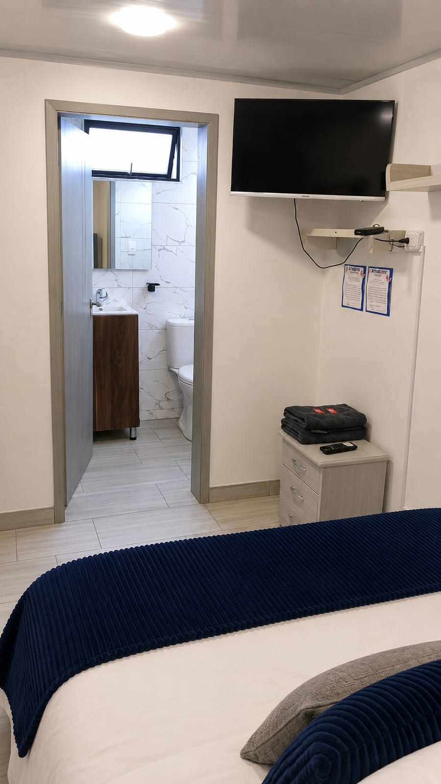 Televisor de pantalla plana en la habitación 302 y puerta abierta al bano privado