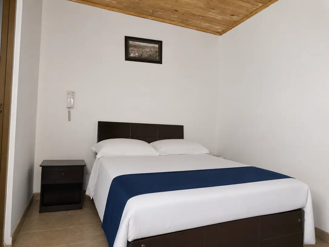 Habitacion doble de Hotel Colonial Confort con ropa de cama blanca y detalle azul